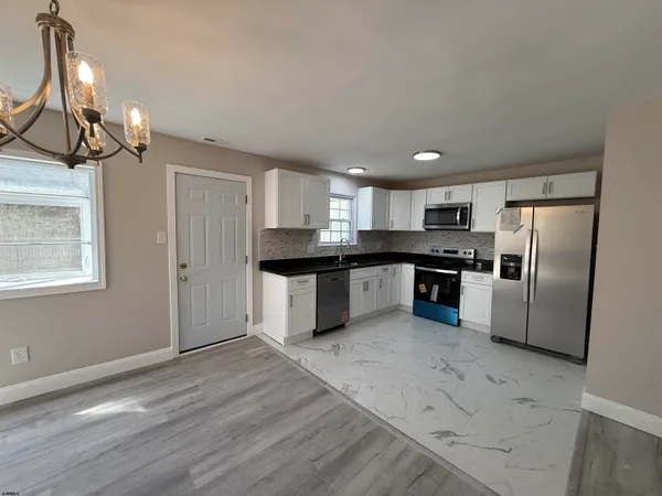 a kitchen with stainless steel appliances granite countertop a refrigerator a sink dishwasher a stove with white cabinets