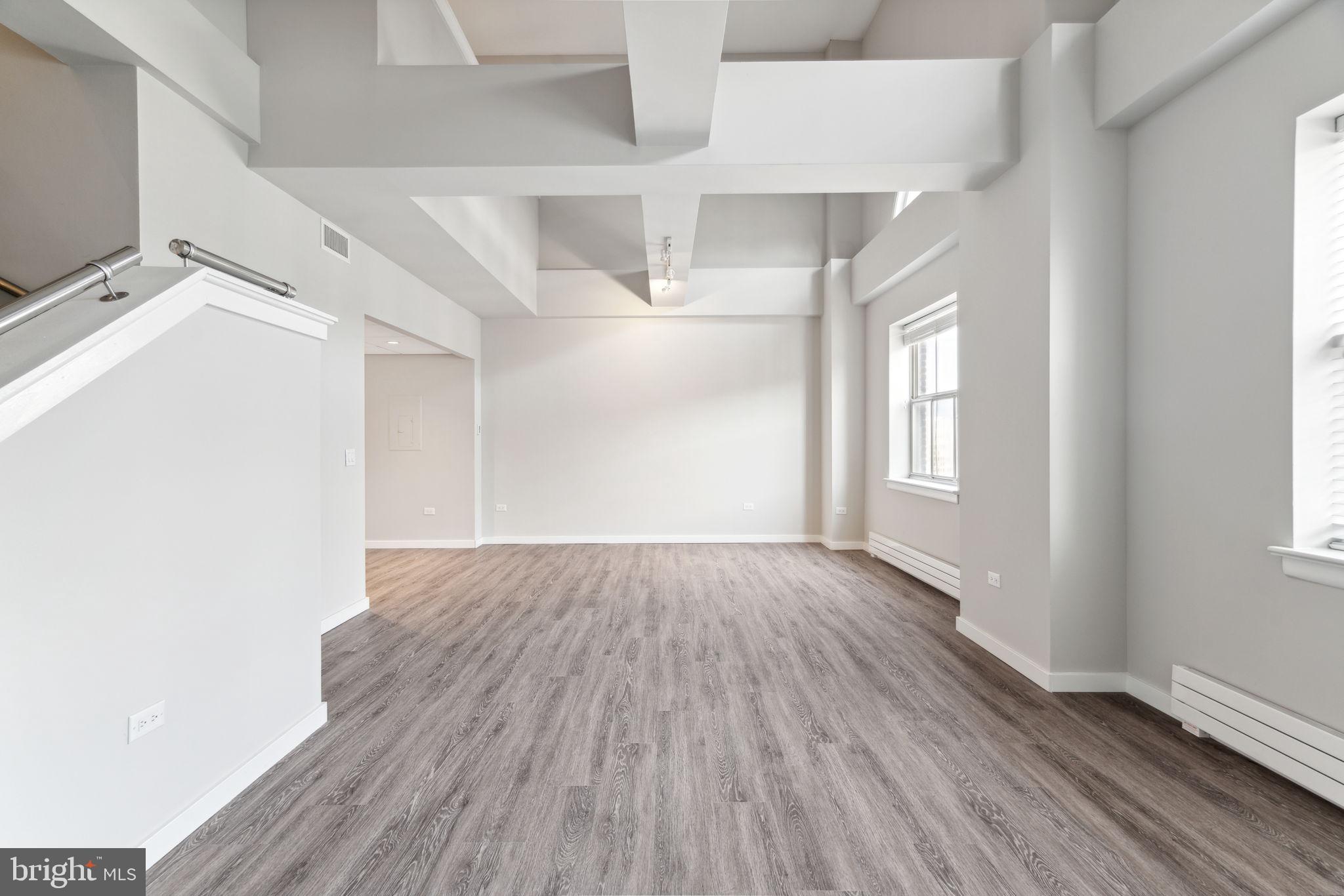 101-111 South 9th Street, Unit PH107 Philadelphia, PA 19107 - Photo 3 of 42 an empty room with wooden floor and windows