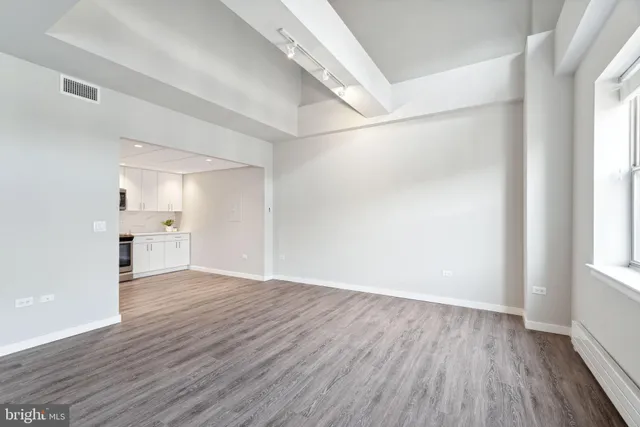 a view of an empty room with wooden floor and a window