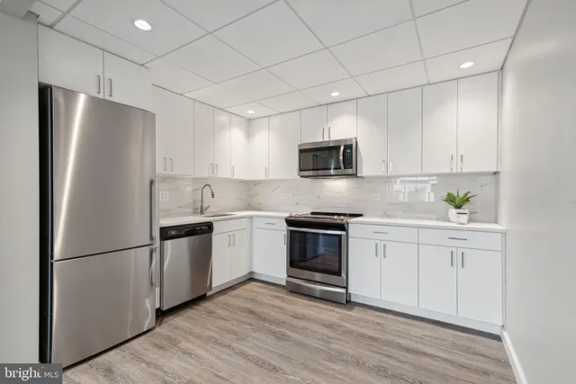 a kitchen with cabinets stainless steel appliances and wooden floor