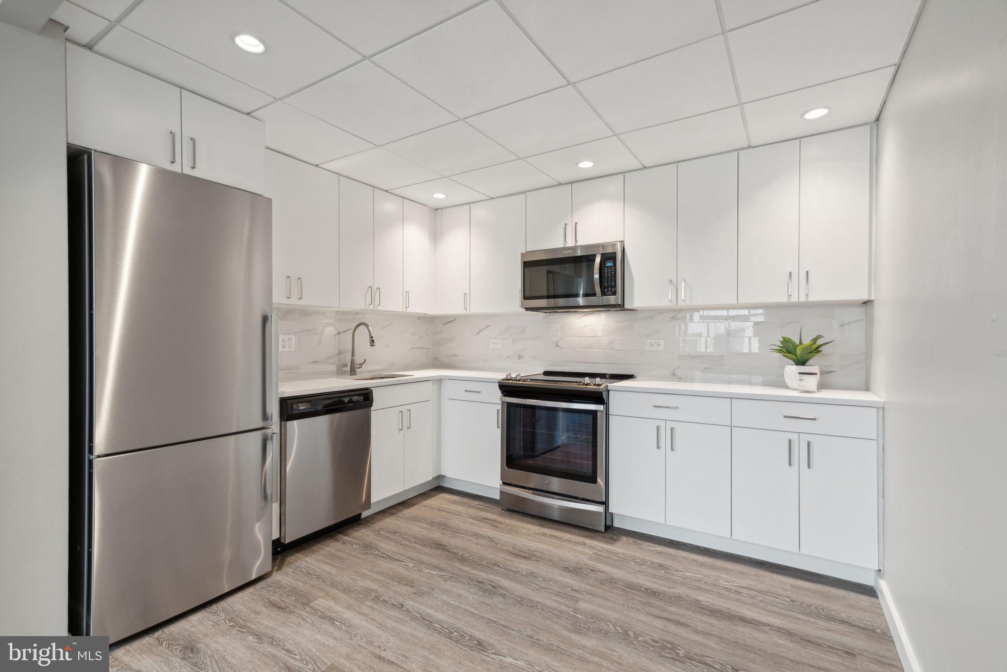 101-111 South 9th Street, Unit PH107 Philadelphia, PA 19107 - Photo 8 of 42 a kitchen with cabinets stainless steel appliances and wooden floor