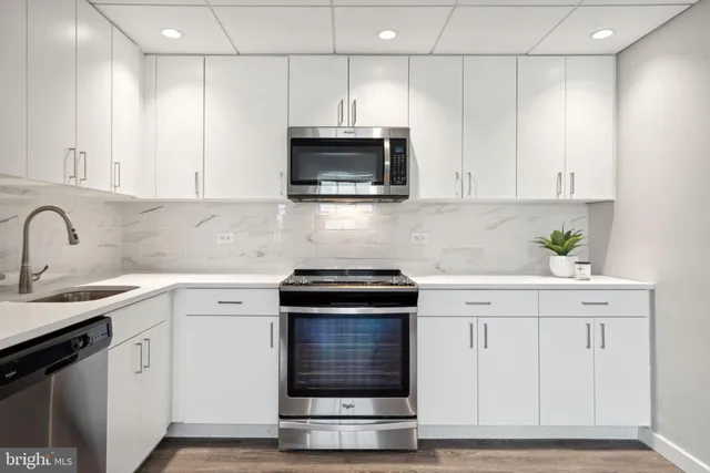 a kitchen with granite countertop white cabinets and stainless steel appliances