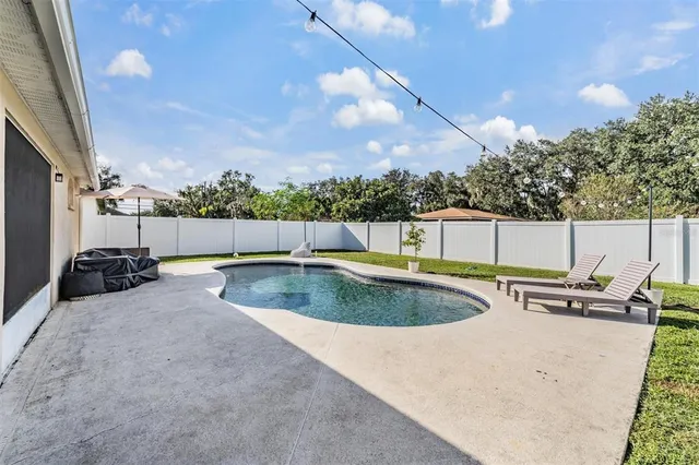 a view of a swimming pool with a patio and a yard