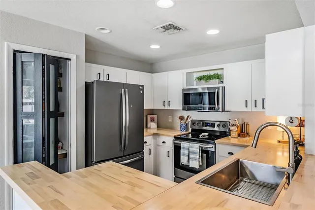 a kitchen with stainless steel appliances granite countertop a refrigerator a sink a stove a microwave and a refrigerator