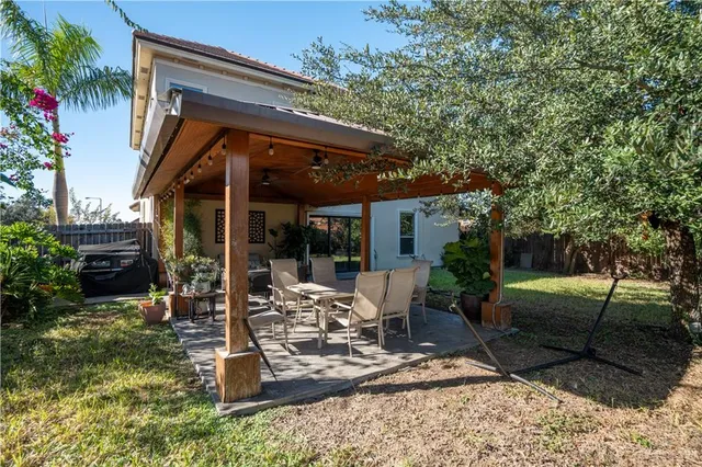 a view of a patio with table and chairs potted plants and large tree