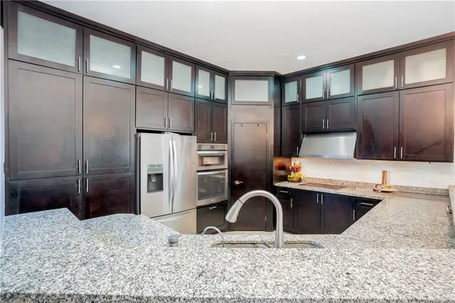 a kitchen with stainless steel appliances kitchen island granite countertop a refrigerator and a sink