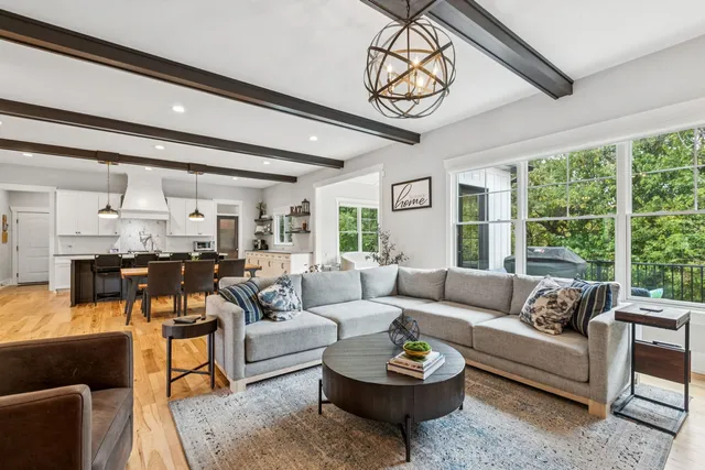 a living room with lots of furniture wooden floor and a large window