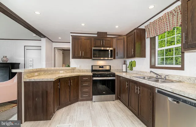 a kitchen with stainless steel appliances granite countertop a sink stove microwave and refrigerator