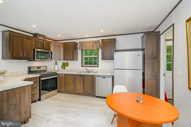 a kitchen with stainless steel appliances granite countertop a refrigerator a stove top oven a sink dishwasher and white cabinets with wooden floor