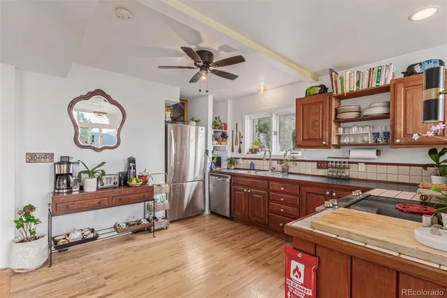 a very nice looking kitchen with granite countertop a stove a sink and dishwasher wooden floor