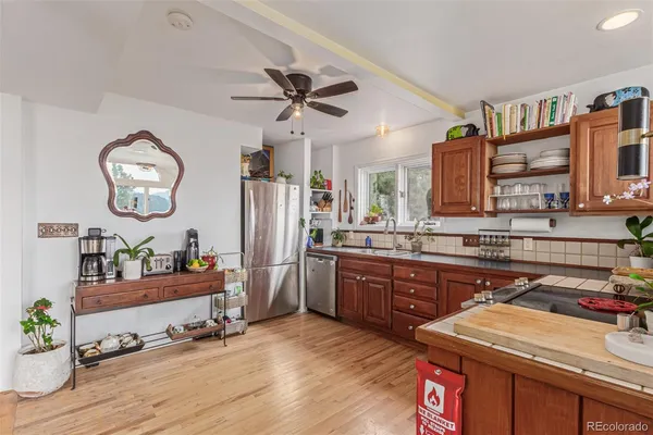 a very nice looking kitchen with granite countertop a stove a sink and dishwasher wooden floor