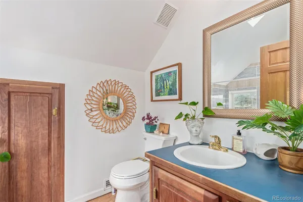 a bathroom with a sink a mirror a toilet and a window