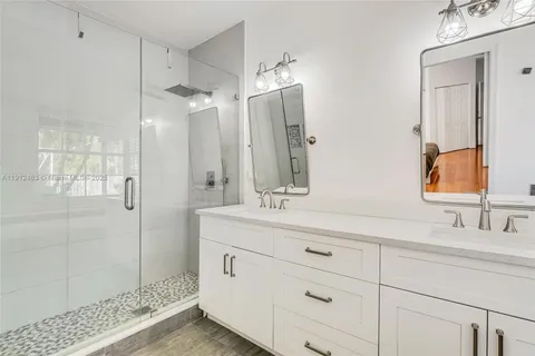 a bathroom with a double vanity sink mirror and shower