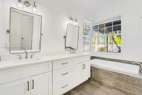 a bathroom with a double vanity sink mirror and bathtub