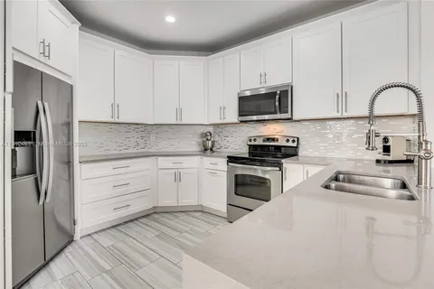 a kitchen with white cabinets stainless steel appliances and a sink