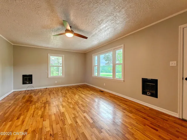 a view of an empty room with window and wooden floor