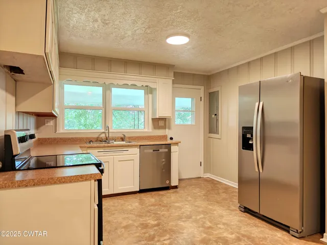 a kitchen with stainless steel appliances granite countertop a refrigerator a sink a stove and island