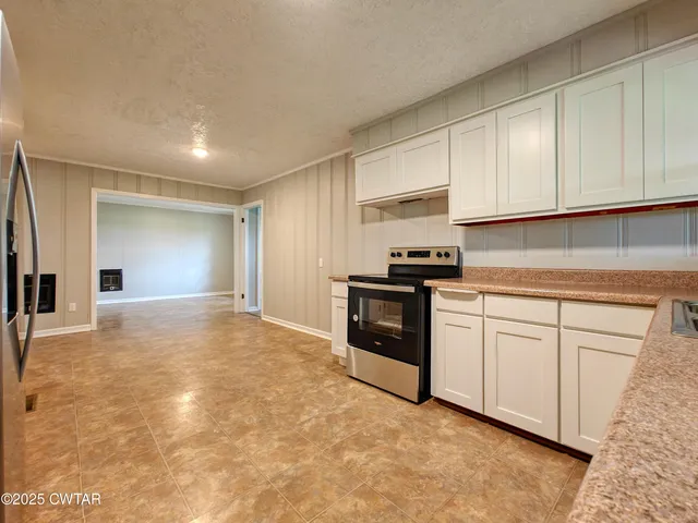 a kitchen with granite countertop a stove a sink and a refrigerator
