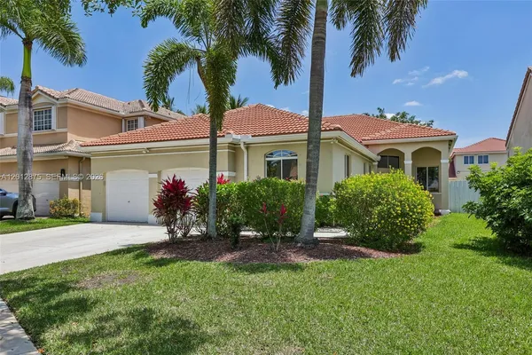 a front view of a house with a garden and palm tree