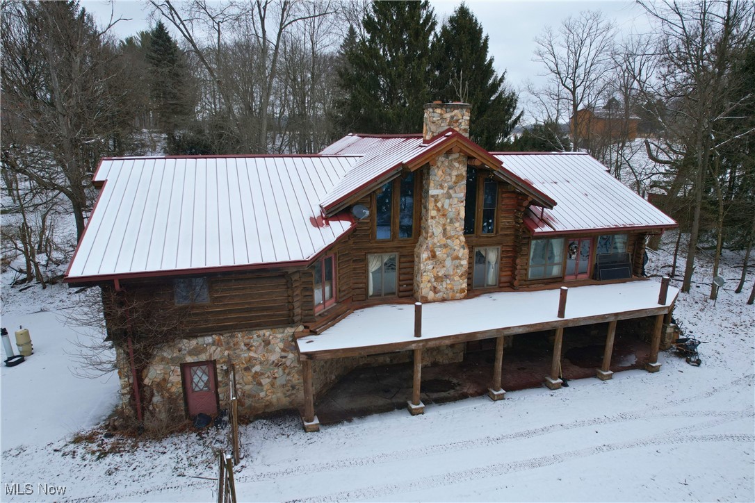 8026 Lee Road Northwest Malvern, OH 44644 - Photo 39 of 44 Snow covered back of property featuring a chimney, log exterior, stone siding, and a metal roof