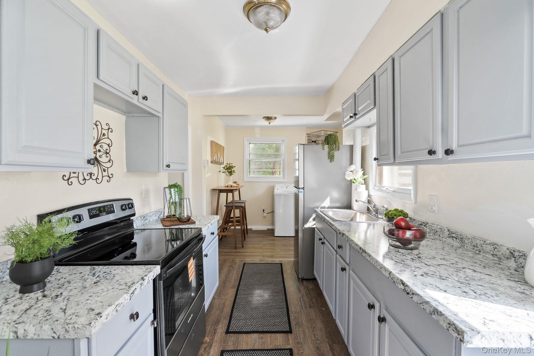 8 Coldenham Road Walden, NY 12586 - Photo 13 of 50 Kitchen with appliances with stainless steel finishes, dark wood-style floors, washer / dryer, gray cabinetry, and light stone countertops