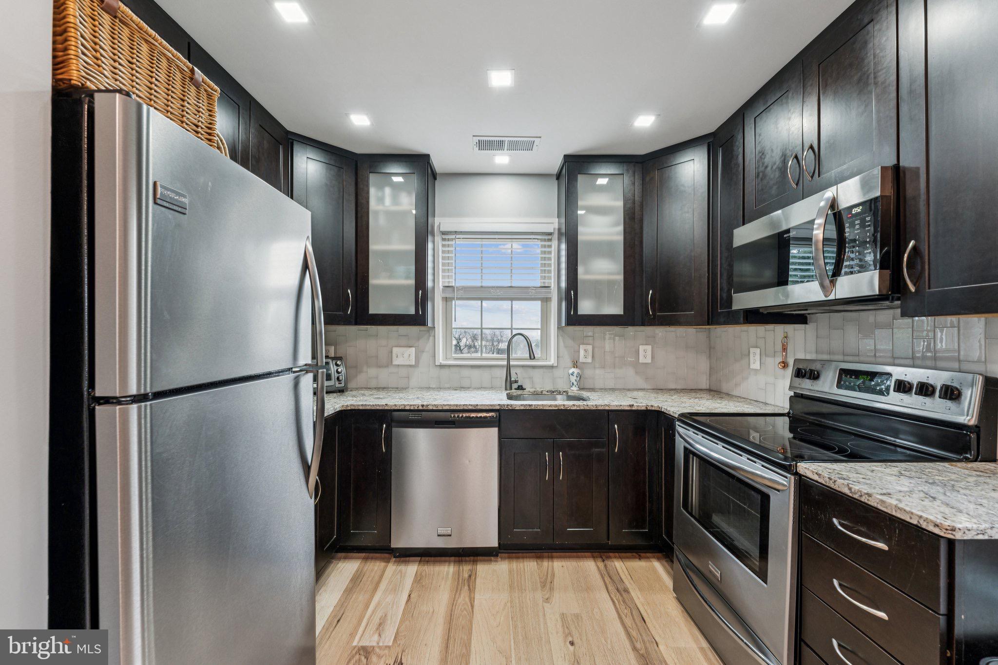 509 Bashford Lane, Unit 6 Alexandria, VA 22314 - Photo 7 of 20 a kitchen with stainless steel appliances granite countertop a refrigerator a sink a stove and a microwave
