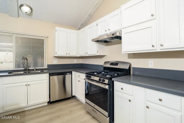 a kitchen with stainless steel appliances a stove and white cabinets