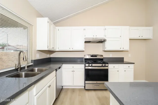 a kitchen with a sink stove top oven and cabinets