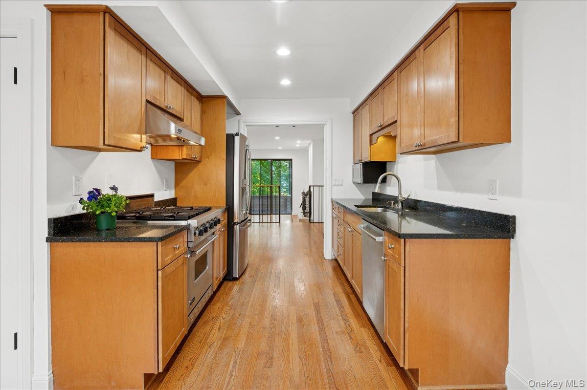 70 Waters Edge, Unit 70 Rye, NY 10580 - Photo 23 of 44 Kitchen with dark stone counters, brown cabinetry, stainless steel appliances, light wood finished floors, and recessed lighting