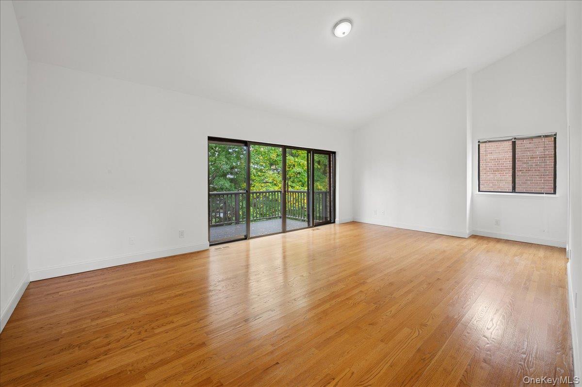 70 Waters Edge, Unit 70 Rye, NY 10580 - Photo 27 of 44 Unfurnished primary bedroom featuring light wood finished floors and high vaulted ceiling and doors to balcony