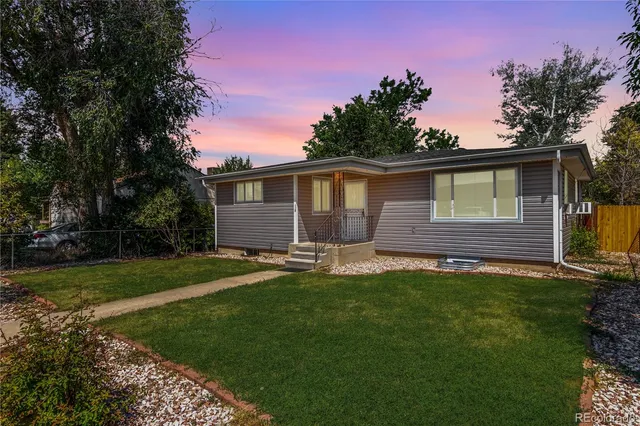 a backyard of a house with table and chairs plants and large tree