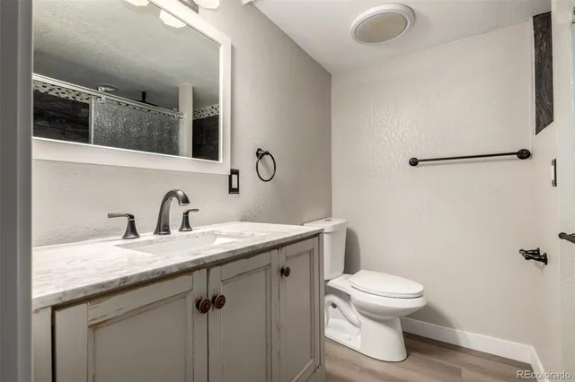 a bathroom with a granite countertop sink a toilet and shower