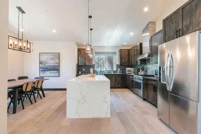 a kitchen with stainless steel appliances kitchen island granite countertop a refrigerator a stove a kitchen island a dining table and chairs