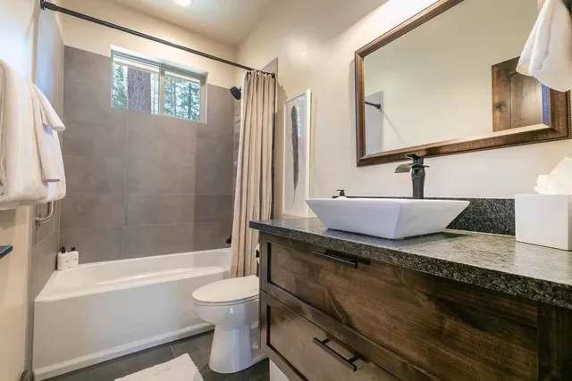 a bathroom with a granite countertop sink a toilet a mirror and bathtub