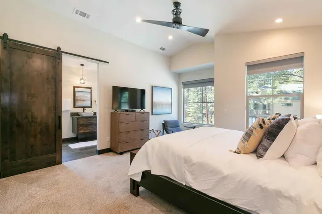 a bedroom with a bed flat screen tv and a large window