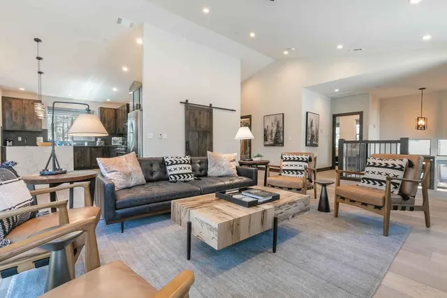 a living room with furniture kitchen view and a wooden floor