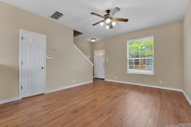 a view of an empty room with wooden floor and a window