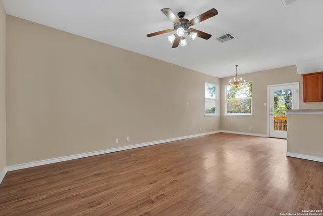 a view of an empty room with a window and wooden floor