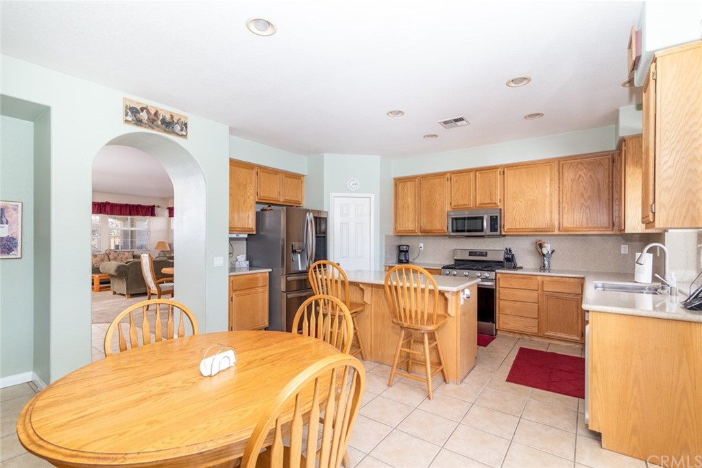 23746 Fieldcrest Lane Murrieta, CA 92562 - Photo 10 of 54 a kitchen with stainless steel appliances kitchen island granite countertop a sink a stove a dining table and chairs