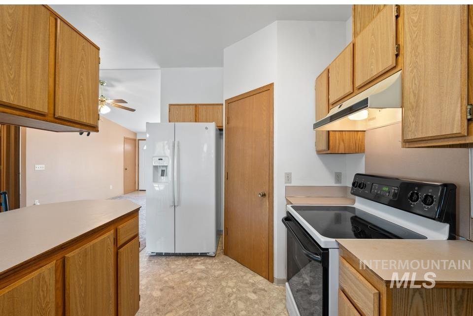 1128 Burrell Avenue, Unit 2 Lewiston, ID 83501 - Photo 9 of 24 Kitchen with range with electric cooktop, white refrigerator with ice dispenser, under cabinet range hood, light countertops, and ceiling fan