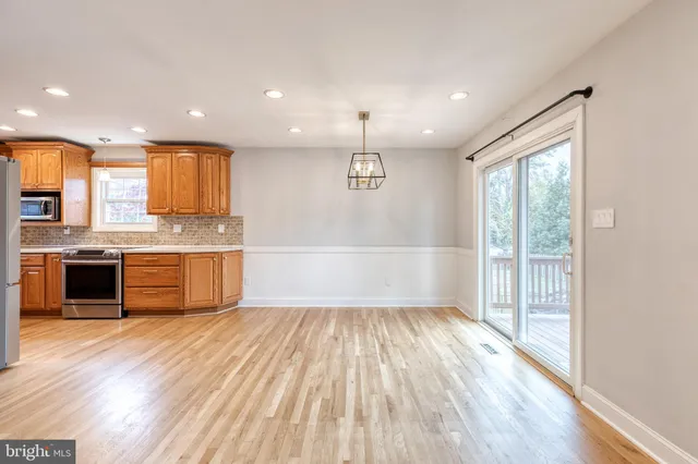 a large kitchen with a large counter top a sink stainless steel appliances and cabinets