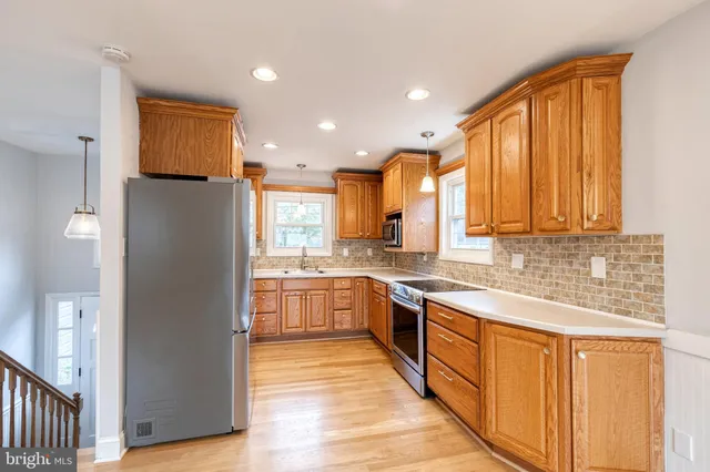 a large kitchen with stainless steel appliances granite countertop a refrigerator a sink dishwasher a stove and white cabinets with wooden floor