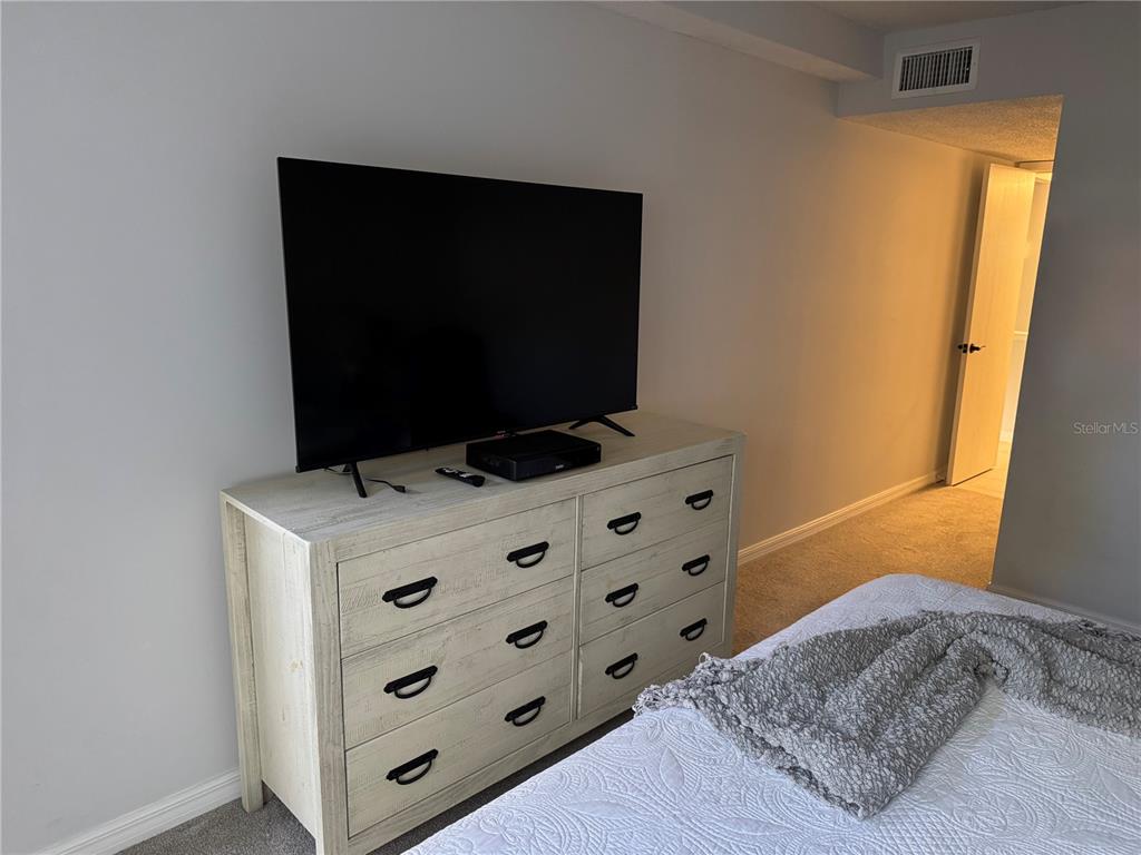 1640 Stickney Point Road, Unit 40101 Sarasota, FL 34231 - Photo 12 of 30 a bedroom with a bed and a flat screen tv