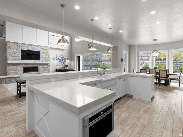 614 East High Lane Alpine, UT 84004 - Photo 74 of 75 Kitchen featuring white cabinets, decorative light fixtures, light wood-style floors, a fireplace, and open floor plan