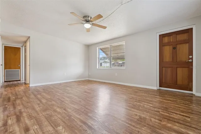 a view of an empty room with a window and wooden floor