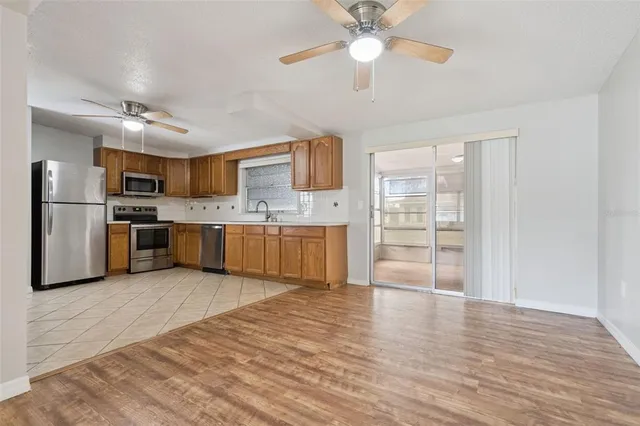 a large kitchen with cabinets stainless steel appliances and a ceiling fan