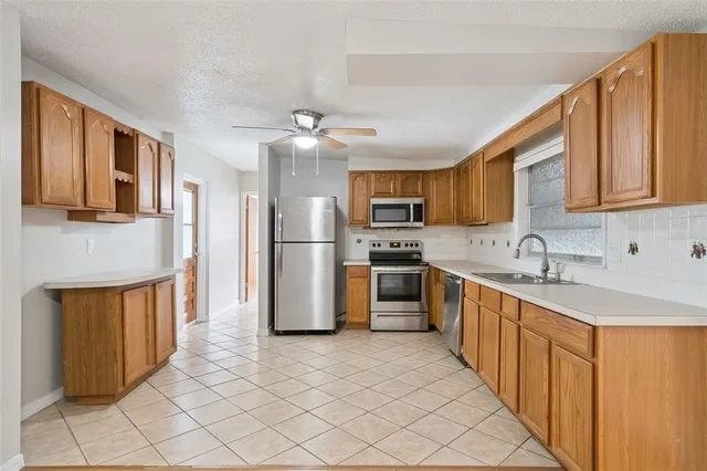 a large kitchen with stainless steel appliances granite countertop a refrigerator a sink dishwasher a stove with wooden cabinets and floor