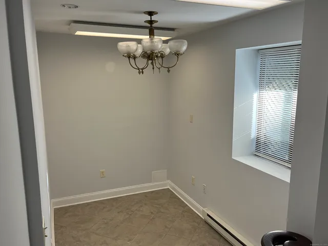 a view of a room with a hanging light and hardwood floor