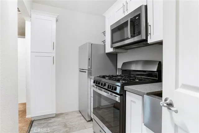 a kitchen with stainless steel appliances granite countertop white cabinets a microwave oven and a refrigerator