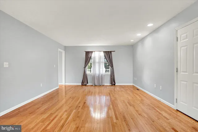 an empty room with wooden floor fireplace and windows